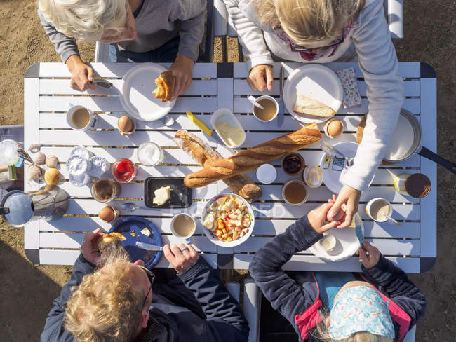 Famiglia seduta sul tavolo all'aperto e fare colazione — Foto stock