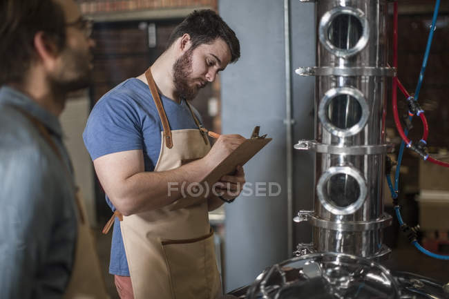 Mann macht sich Notizen auf Klemmbrett — Stockfoto