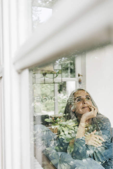 Femme souriante assise derrière la vitre — Photo de stock