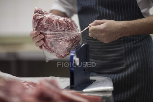 Butcher packing raw meat in butchery — Stock Photo