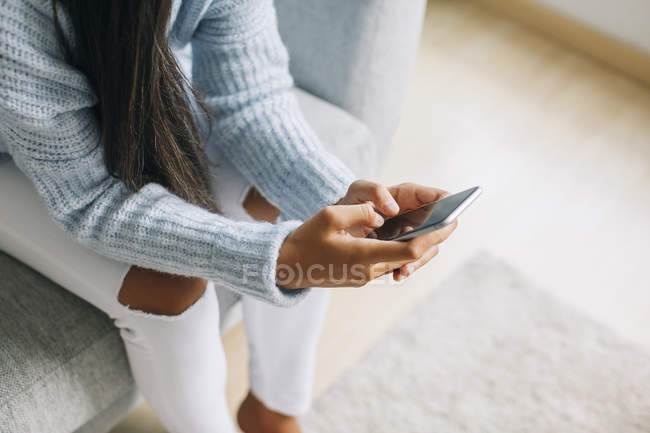 Woman sitting on couch and text messaging — Stock Photo