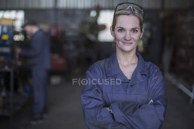 Портрет уверенной женщины-механика, стоящей в мастерской — стоковое фото