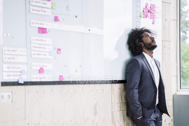 Businessman leaning against white board — Stock Photo
