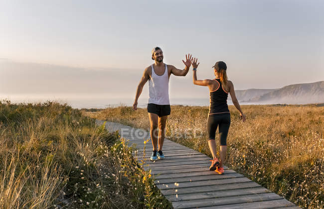 Couple hitting five on the beach in the evening — Stock Photo