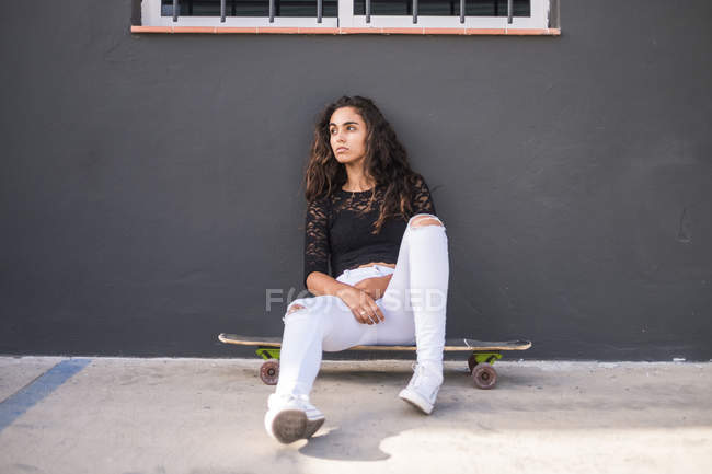 Ragazza adolescente seduta su skateboard — Foto stock