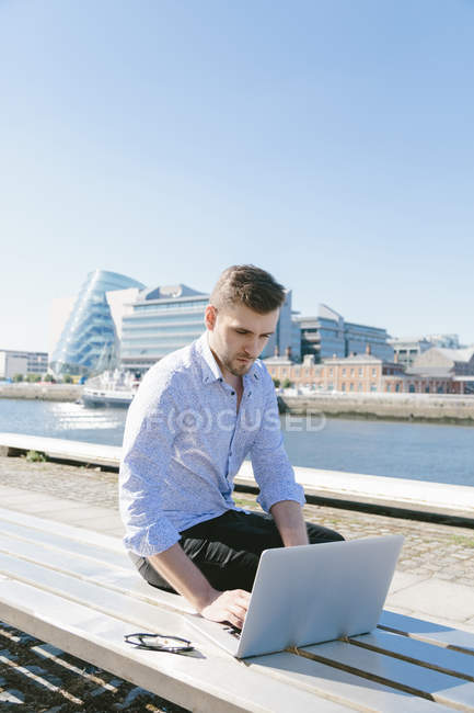 Бізнесмен сидить на лавці за допомогою ноутбука — стокове фото