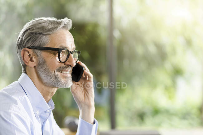 Улыбающийся мужчина с седыми волосами и бородой по телефону — стоковое фото