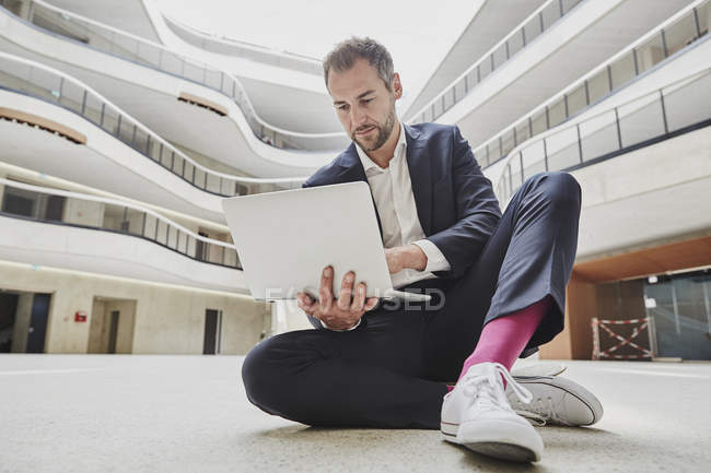 Geschäftsmann sitzt in Bürogebäude auf dem Boden — Stockfoto