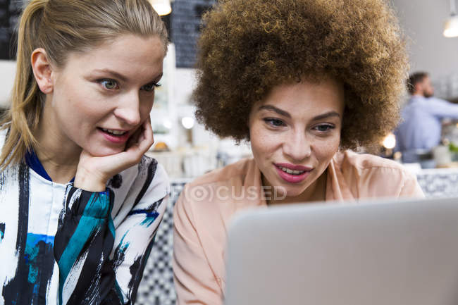 Duas jovens mulheres usando laptop em um café — Fotografia de Stock