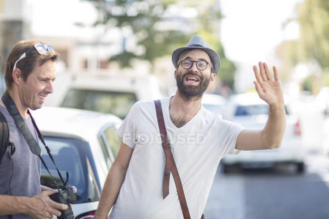 Чоловік з другом у місті висікає таксі — стокове фото