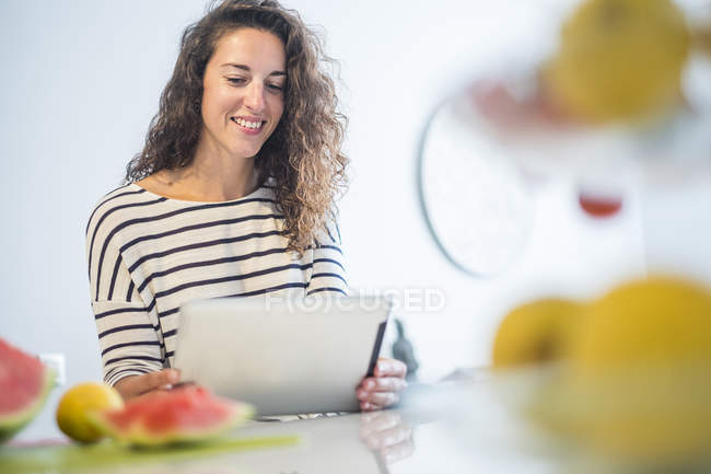 Retrato de mujer sonriente usando tableta en casa - foto de stock