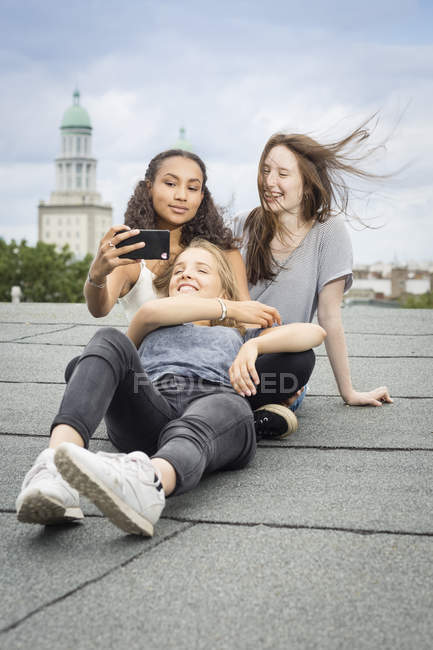 Germany Berlin Three Friends Sitting On Roof Top Taking Selfie With Smartphone Joy Outdoor Stock Photo 173746160