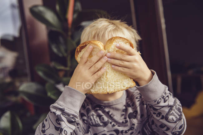Kleiner Junge bedeckt Gesicht mit einer Scheibe Weißbrot — Stockfoto
