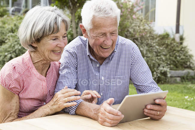 Happy senior couple using digital tablet in garden — Stock Photo