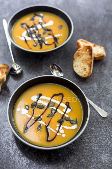 Кремовий гарбузовий суп у чорній мисці на сірій тарілці — стокове фото