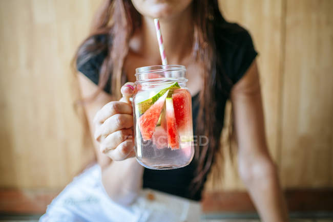 Primo piano della donna che tiene in mano un bicchiere d'acqua con anguria — Foto stock