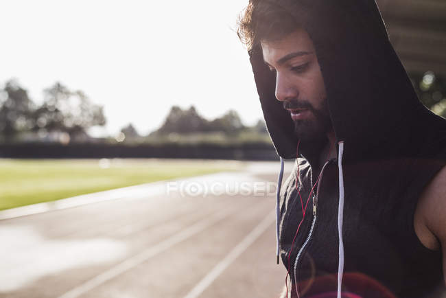 Young man wearing hooded top on tartan track — Stock Photo
