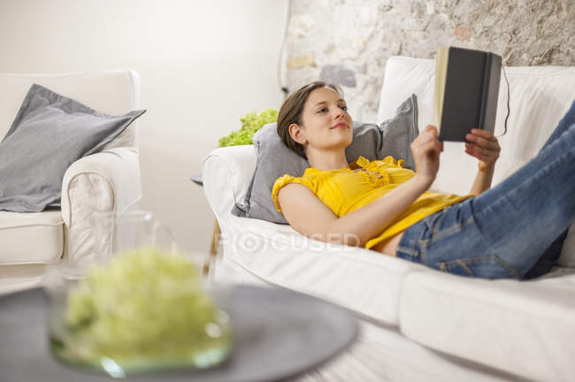 Жінка, лежачи на дивані і читав книгу — стокове фото
