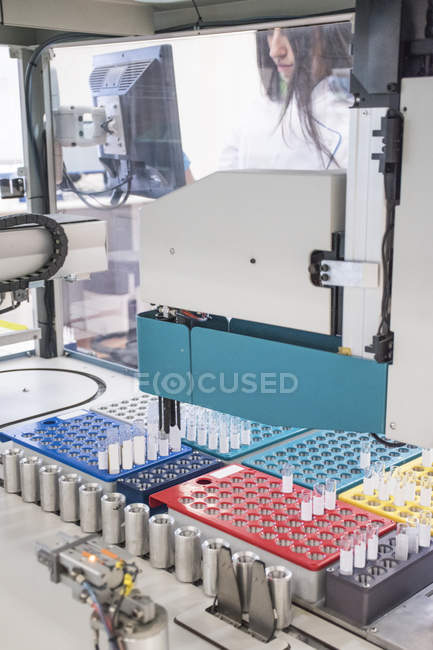 Técnico de laboratorio en laboratorio analítico que toma la prueba mirando el aliquoter automatizado - foto de stock