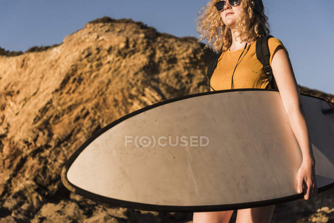 Teenage girl on the beach carrying surfboard — Stock Photo