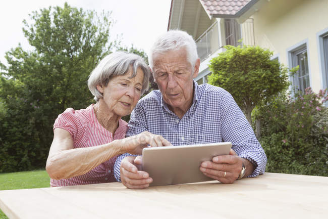 Старшая пара с помощью цифрового планшета в саду — стоковое фото