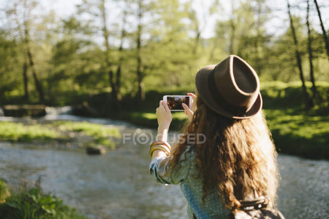 Rückansicht von voung woman beim Fotografieren mit dem Smartphone — Stockfoto