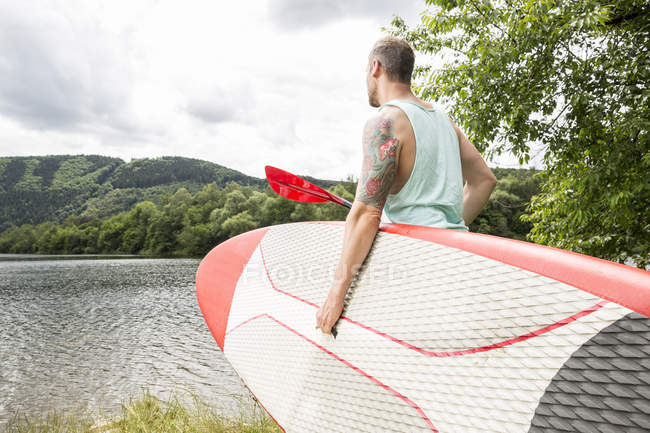 Uomo portando stand up paddle board — Foto stock