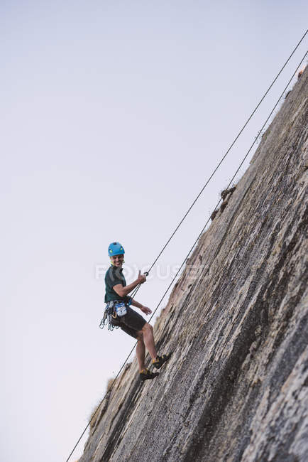 Young man climbing a rock wall — Stock Photo