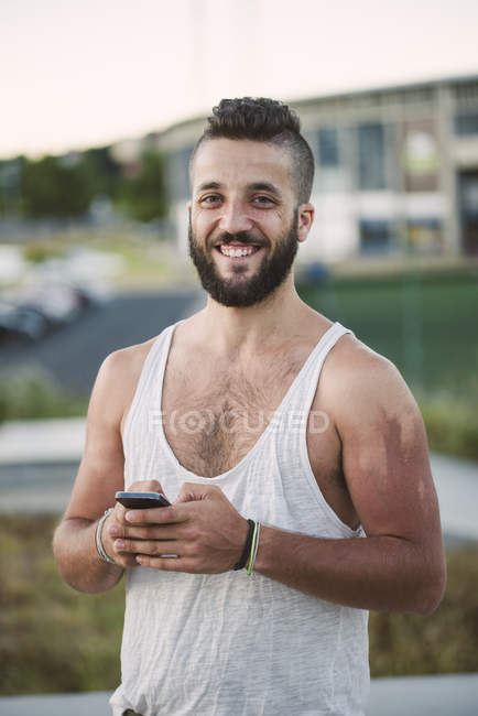 Homme souriant tenant smartphone — Photo de stock