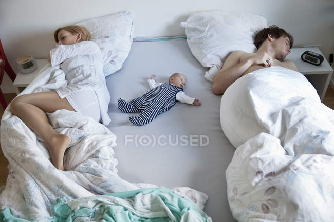Genitori che dormono con il neonato a letto — Foto stock