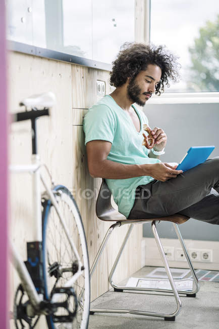 Designer sitting on chair and using tablet — Stock Photo