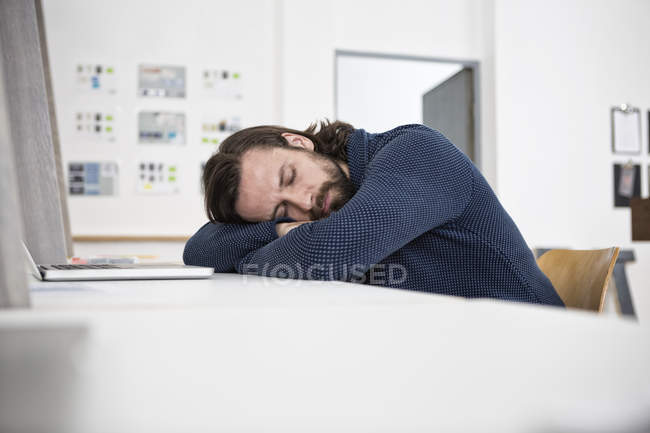 Мужчина спит на столе в офисе — стоковое фото