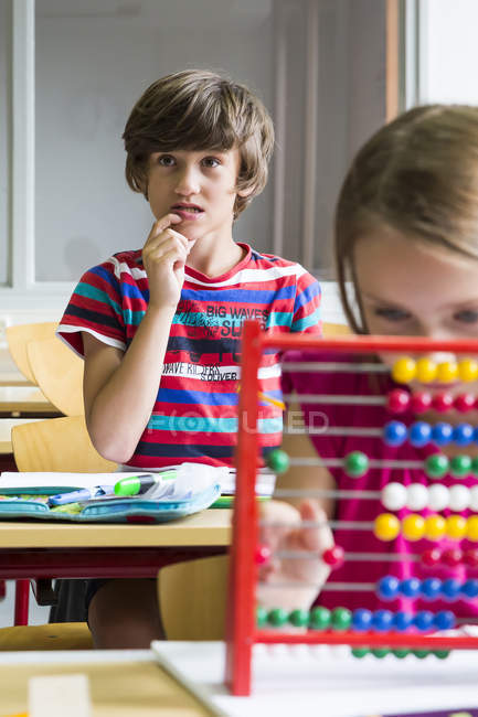 Portrait of pensive pupil sitting at classroom — Stock Photo