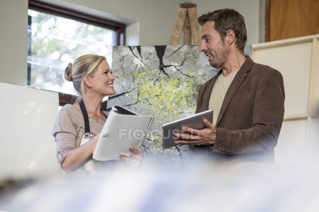 Female painter speaking with man, holding and digital tablet — Stock Photo