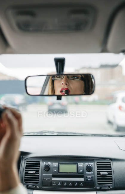 Woman in car applying lipstick — Stock Photo