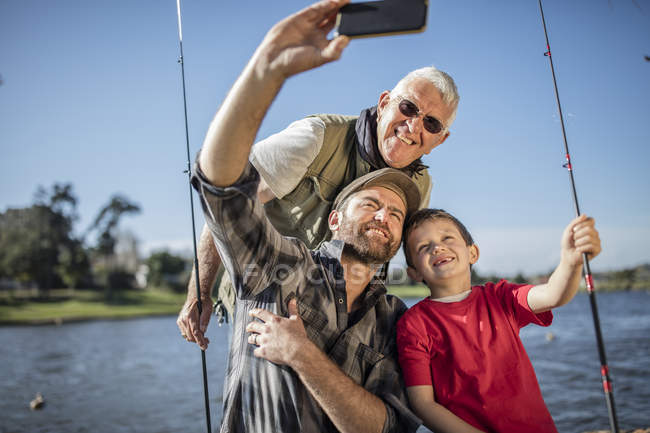 Abuelo, padre e hijo tomando una selfie con cañas de pescar — Cielo azul,  familia - Stock Photo | #173756254