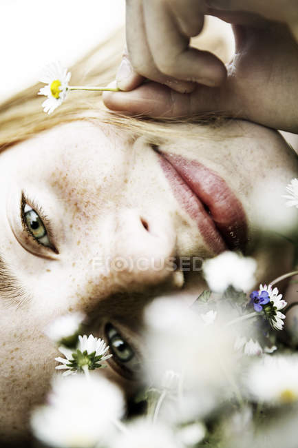 Smiling girl lying on field of flower — Stock Photo