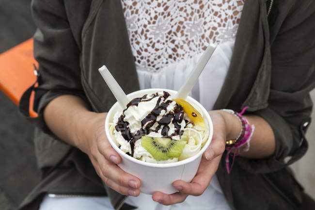 Hände eines Teenagers mit einer Tasse Eis mit Früchten — Stockfoto