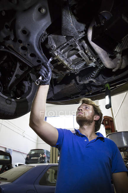 Mechaniker repariert hängendes Auto in seiner Werkstatt — Stockfoto