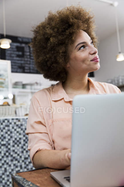 Lächelnde junge Frau mit Laptop in einem Café — Stockfoto