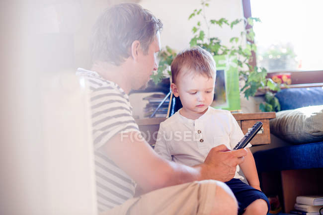 Pai e filho brincando com controle remoto em casa — Fotografia de Stock