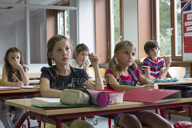 Attentive pupils sitting at classroom in school — Stock Photo