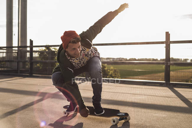 Hombre joven montando monopatín en el nivel de estacionamiento - foto de stock