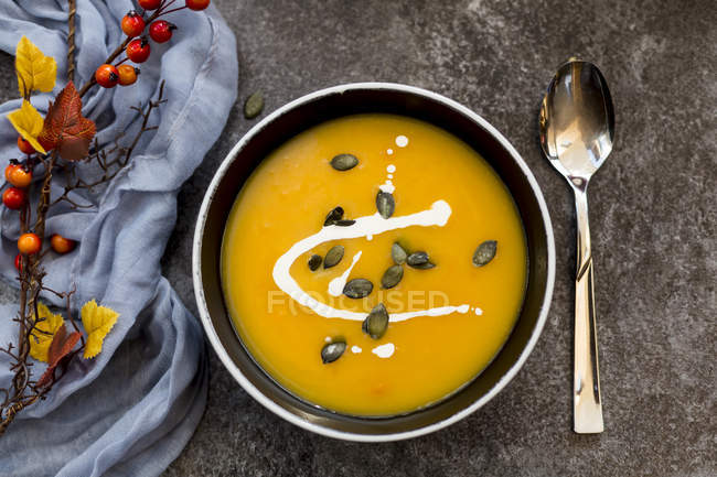 Soupe à la citrouille en crème dans un bol noir sur une table grise — Photo de stock