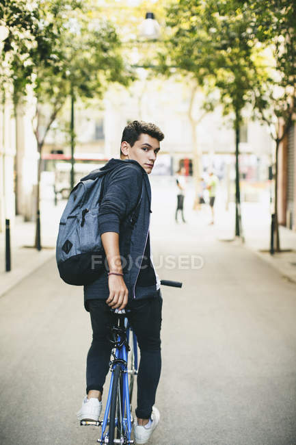 Adolescente com uma bicicleta fixa na cidade, andando e olhando para a câmera — Fotografia de Stock