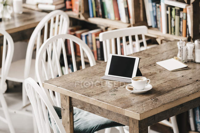 Tisch im Café mit Tasse Kaffee und digitalem Tablet — Stockfoto