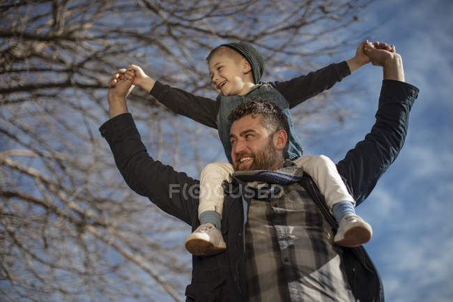 Padre cargando a su hijo en hombros - foto de stock