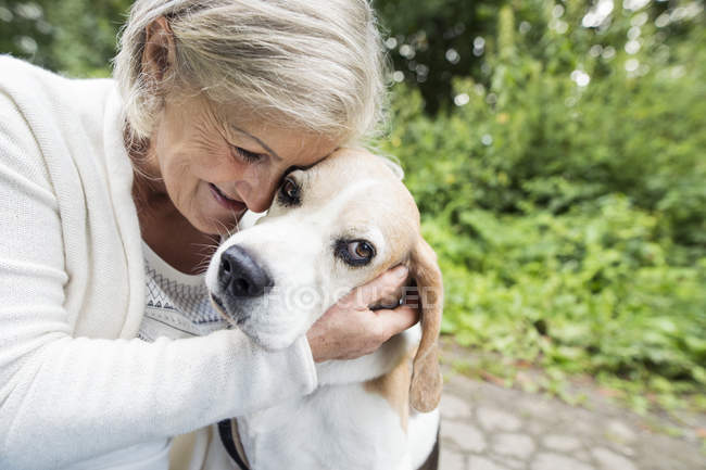 Feliz anciano mujer abrazo perro - foto de stock
