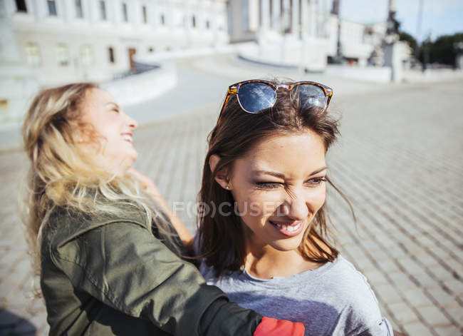 Austria, Vienna, two young women having fun in front of the parliament building — Stock Photo
