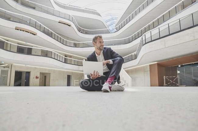 Geschäftsmann sitzt in Bürogebäude auf dem Boden — Stockfoto